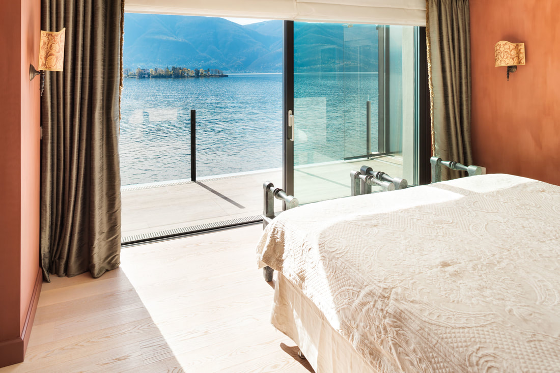 Luxury interior room with with bed facing the glass window that leads out to sea